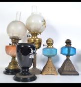 A collection of early 20th century oil lamps to include orange glass reservoir,