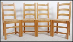 A set of four 20th century light oak ladder back dining chairs with rattan weave seats raised on