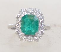 A platinum emerald and diamond ring set with a central emerald of approx 2cts surrounded by a halo