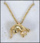 A hallmarked 18ct gold pendant necklace strung with a figural brooch pendant in the form of a cat