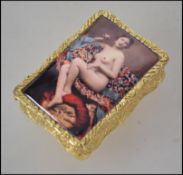 A gold plated silver ladies pill box having an enamel set erotic maiden to the top with chase