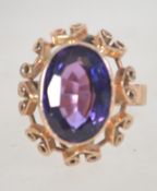 An early 20th century 15ct gold ring set with a purple oval cut stone, possibly amethyst,