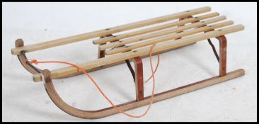 A vintage 20th century wooden sleigh having slated seat rail and iron runners.