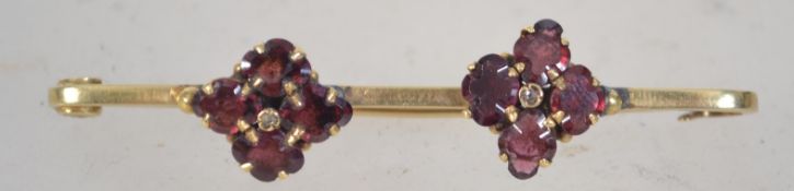 A 15ct gold and garnet bar brooch having eight quatrefoil cut garnet stones mounted to the bar.