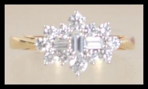 A hallmarked 18ct gold and diamond cluster ring with central baguette diamonds surrounded by round