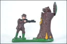 A novelty cast iron painted money box of an archer firing into a tree stump with hinged lid having