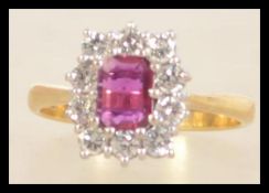 A hallmarked 18ct gold diamond and red stone ring set with a central emerald cut red stone