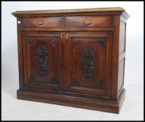 A 19th century carved English oak sideboard raised on a plinth base with twin cupboard doors having