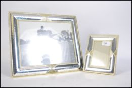 A pair of 20th century silver plated glazed easel back picture frames having a gilt ribbon edge.