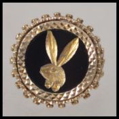 A 9ct gold gentlemans signet ring. The shank with lattice worked shoulders, playboy token to centre.