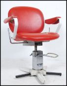 A vintage retro 20th century barbers chair having rise and fall pedal finished with a faux red