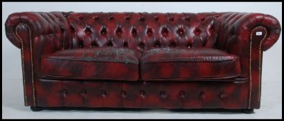 An antique style oxblood red leather Chesterfield sofa settee having buttoned back leather scrolled