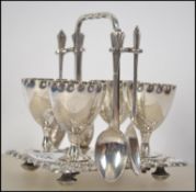 A silver plated four persons breakfast egg service consisting of four egg cups on stand with spoons.