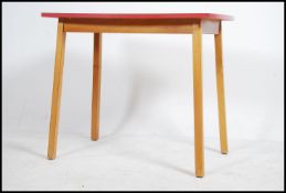 A vintage retro mid 20th century kitchen dining table having a red formica top raised on tapered