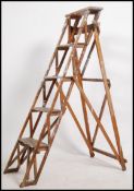 A vintage early to mid 20th century industrial wooden skeleton / trellis step ladder with cast iron