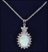 A silver and large opal necklace and pendant surrounded by cz's and set to a fine link chain.