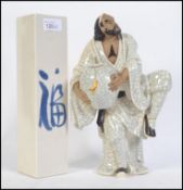 A late 19th century / early 20th century crackle glaze Japanese ceramic figure of a man raised on