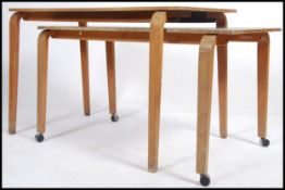 A pair of mid century stacking desks being raised on bentwood supports with inset green tops.