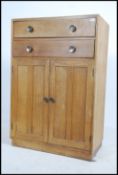 A vintage mid 20th century oak utility tall boy chest cupboard comprising of a series of drawers