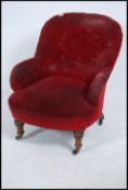 A Victorian 19th century mahogany tub armchair being raised on turned legs with button backed red