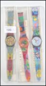 A group of three cased collectors Swatch watches of different designs retaining paperwork and cases.