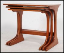 A 1970's G-Plan teak wood nest of tables raised on shaped supports with bow stretchers to each
