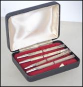 A cased set of four silver stamped Sterling Silver bridge pens, each with a carved suite.
