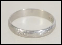 A hallmarked platinum band ring with etched foliate and star decoration.
