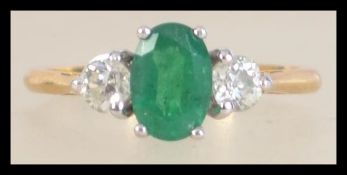 A hallmarked 18ct gold emerald and diamond three stone ring. Hallmarked London. Size O.