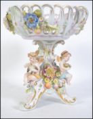 A continental Meissen type porcelain centrepiece raised on a cherub - putti base with lattice
