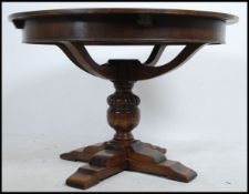 A large 20th century French oak circular extending dining table being raised on bulbous turned