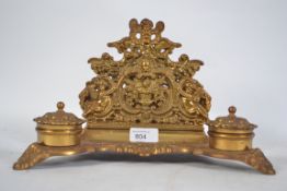 A Victorian gilded brass rococo desk tidy inkwell having twin hinged pots with cherub adorned