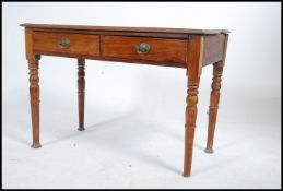 A Victorian mahogany writing table / side table of reduced height raised on turned legs with twin
