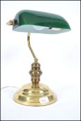 A pair of 20th century bankers desk lamp having a green glass shade being raised on a brass stands