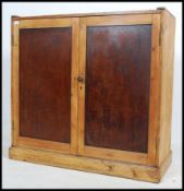An early 20th century Industrial waxed pine school cupboard with twin doors enclosing a shelved