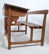 A good vintage 20th century solid oak double school desk having a slatted bench seat with hinged