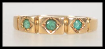 A Victorian 18ct gold band ring set with three green stones.