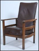 A 1930's beechwood reclining fireside armchair being raised on squared legs with brown vinyl