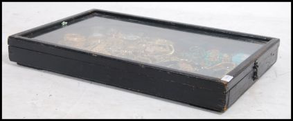 An early 20th century ebonised jewellery display case with hinged glass top with clasp having