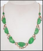 A vintage 14 ct gold and jade necklace with carved jade panels set within a foliate mount having a