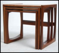A 1970's retro G-Plan Kelso nest of tables being raised on squared legs with peripheral stretchers,