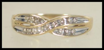 A hallmarked 9ct gold and diamond kiss crossover ring. Weight 2.6g. Diamonds approx 15pts. Size T.