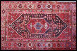 An early 20th century Persian rug with red ground having central lozenge medallion with scrolled