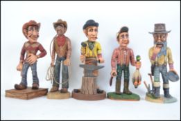 A collection of 5 hand carved and painted wooden figurines to include a cowboy, a ranchman,