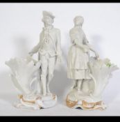 A pair of 19th century parian ware figurines of a dandy gent and a maiden raised on cornucopia