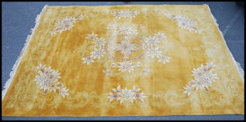A large 20th century Chinese rug having deep pile in yellow with cream decoration and tassled ends