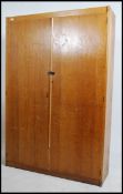 A 20th century Industrial beech wood school cupboard on plinth base with twin full length doors