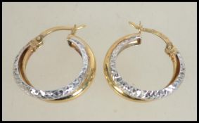 A pair of hallmarked 9ct white and yellow gold hoop earrings with star cut decoration. Weight 1.
