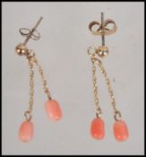 A pair of 9ct gold and coral drop earrings. Measures approx 1.25 inch drop. Weight .9g.