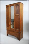 An early 20th century oak single wardrobe having a central mirror door over single drawer plinth